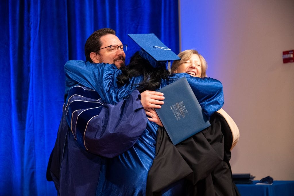 Two people hug a graduate