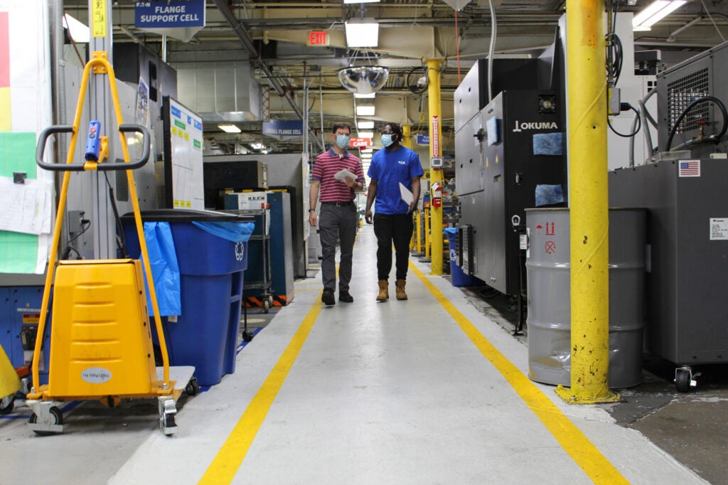Anthony Dickey and his supervisor walk through a factory floor.