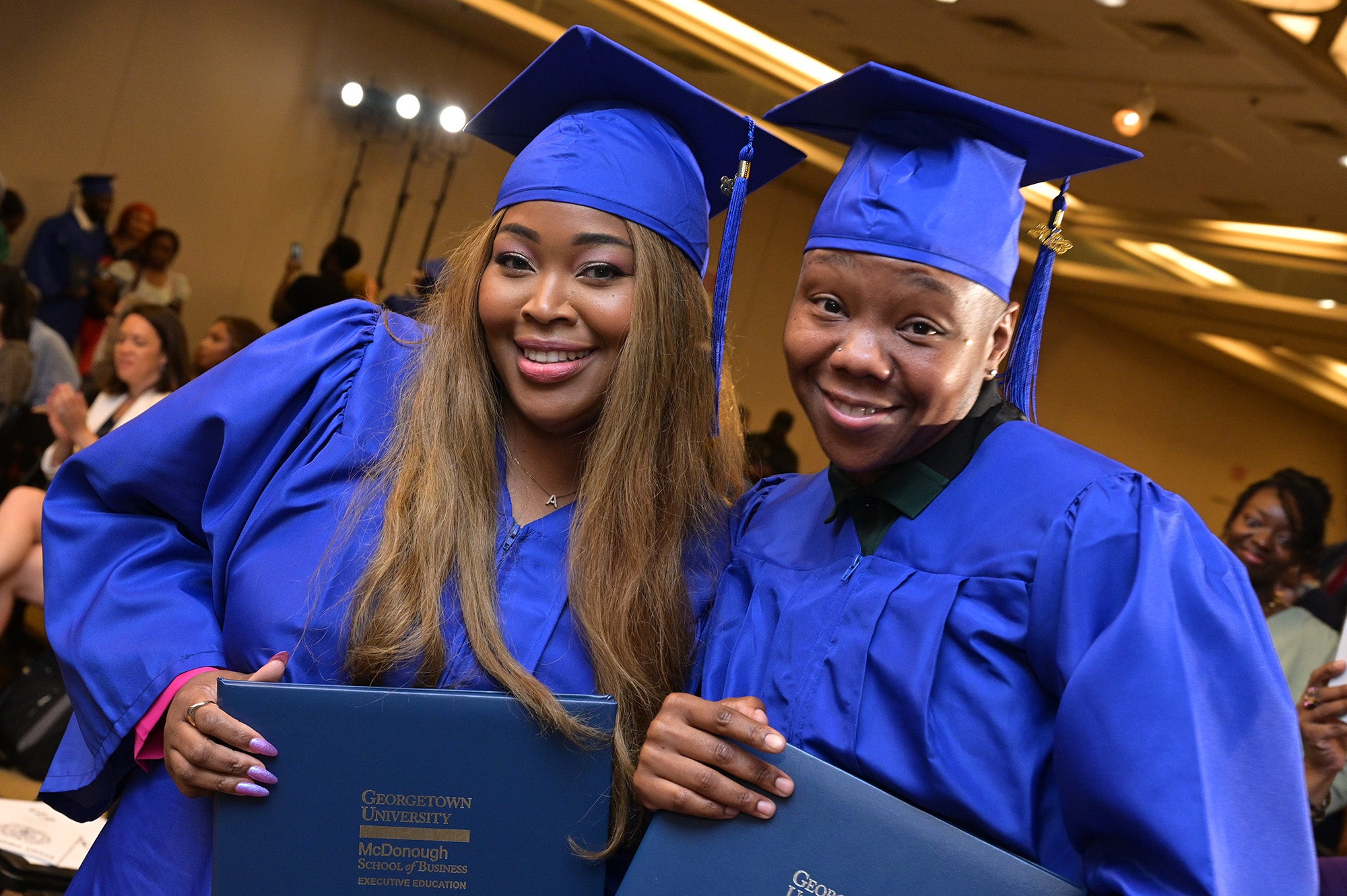 Two Pivot graduates in cap and gown