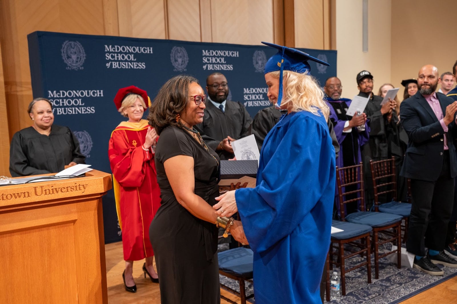 Sheryl Daniel (left) presents the Ryan D. Matthew award to Shannon Sisney (left) on stage at graduation