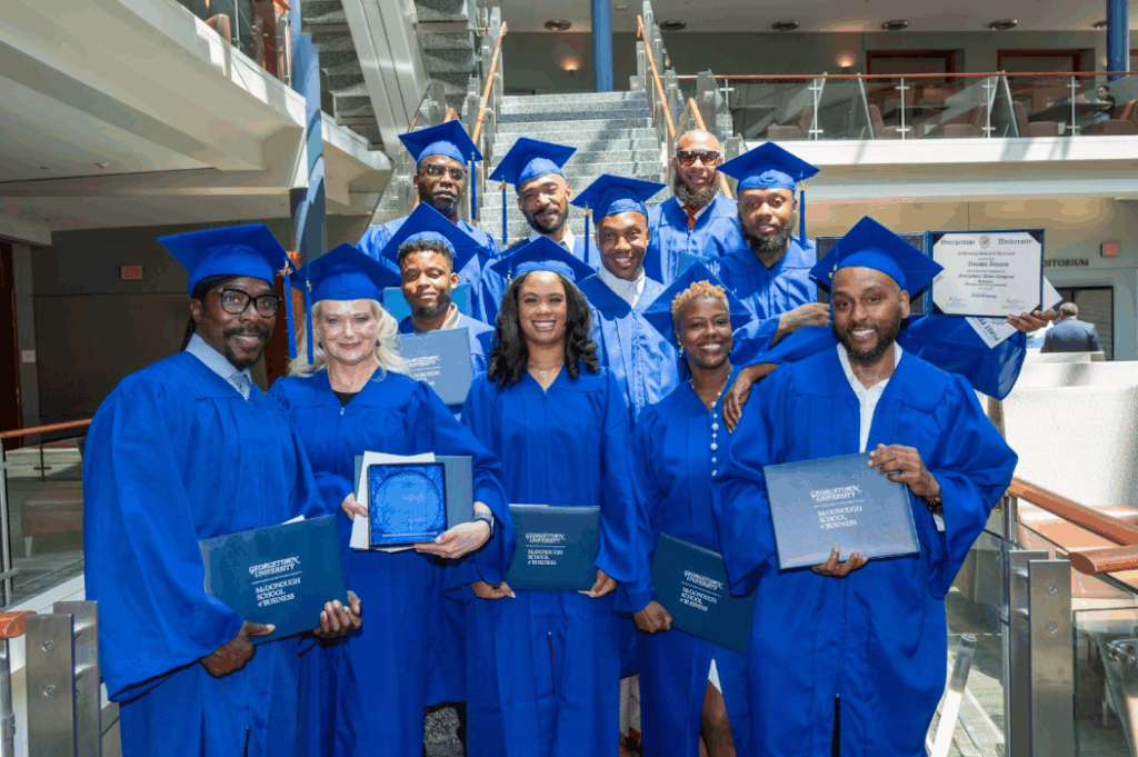 Group photo of Pivot fellow graduates holding their certificates on the steps inside the Rafik B. Hariri Building
